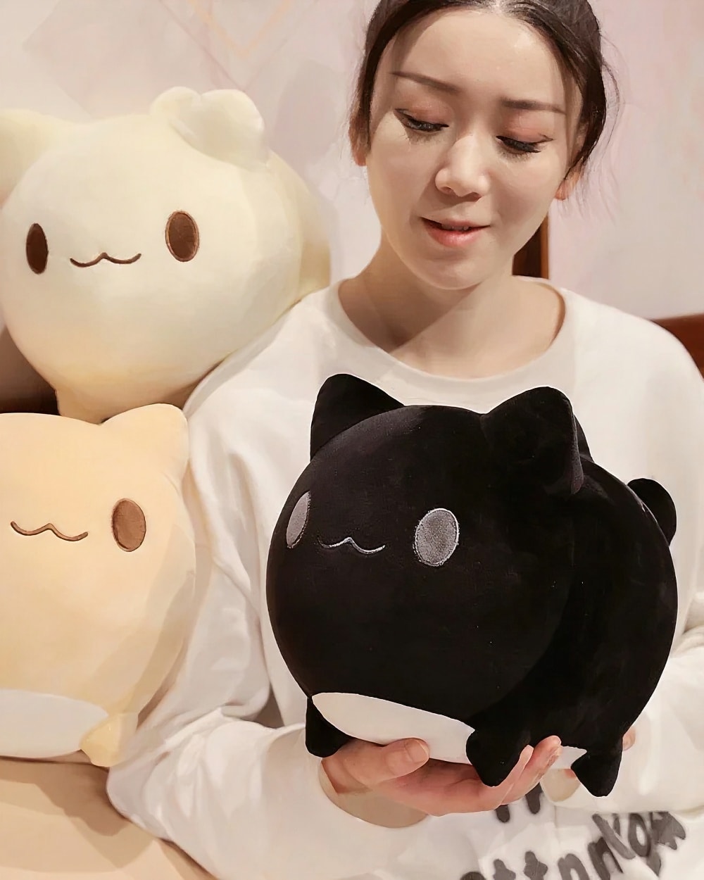 Black round neko plushie displayed in a person's hand.