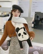 Woman wearing an animal winter scarf featuring a panda design with a boat.