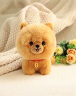 A soft, tan puppy collectible plush with a pink nose and tongue, displayed on a blanket.