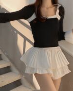 White pleated coquette aesthetic skirt layered with a black top, Korean fashion style.