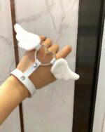 White winged love bracelets on a hand, featuring heart and angel wings design.