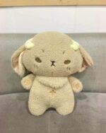 Close-up of a kawaii space sheep plushie, soft and beige with small ears and horns.