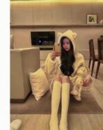 A person wearing kawaii hooded pajamas with knee-high socks, holding a plush toy.