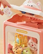 Pink kawaii mini claw machine with plush toys inside and a grabbing arm.
