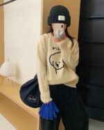 Woman wearing a beige puppy doodle sweater with a cute dog print.