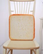Toast Plush Pillow, a square plush shaped like toast, resting on a chair.
