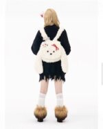 White and black plushie korean style backpack with bow detail, worn as a crossbody bag.