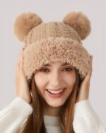 Cream-colored bear ears hat worn by a woman, featuring fluffy pom-poms.