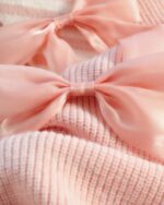 Close-up of a dollcore pink sweater with satin bows.