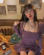 Purple lace gothic aesthetic dress worn by a woman in a vintage-style setting.