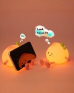 Small peach night lamp alongside a smartphone and television.