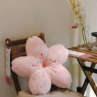 Pink sakura flower pillow resting on a wooden chair.