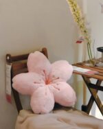 Pink sakura flower pillow resting on a wooden chair.