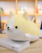 A cute, yellow kawaii corgi plushie lying on a stack of books.