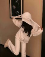 A person wearing fluffy bunny pajamas with a hood and ears.