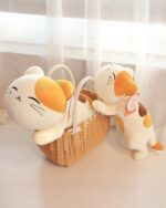 Two kawaii cat plushies in a wicker basket, featuring orange and white coloring.
