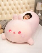 Large pink molang bunny plushie, kawaii stuffed animal resting on a bed.