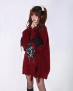 A maroon loose gothic sweater with spider web embroidery, worn by a model.