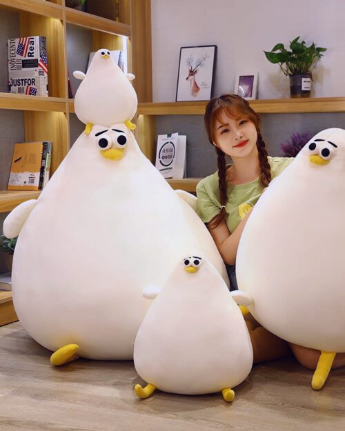 Three Ultra Round Chicken plushies displayed with a person in a room setting.