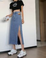 Woman wearing a light blue korean denim skirt with side slits and distressed hem.
