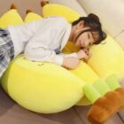 Yellow banana plushies, three pack, resting on a sofa.