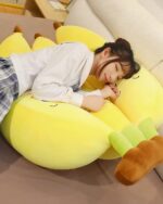 Yellow banana plushies, three pack, resting on a sofa.