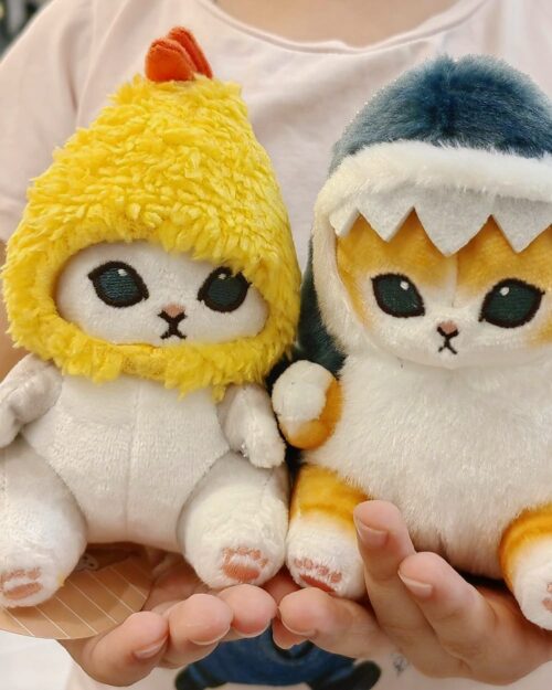 Two cute Chibi shark cat plushies, one yellow and one blue, held in hands.