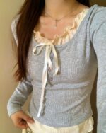 Close-up of a grey vintage aesthetic sweatshirt with a white lace bow detail and ruffled shirt underneath.