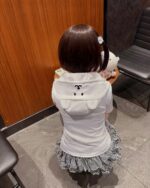 Back view of a child wearing a Jojifuku aesthetic hoodie with a ruffled skirt and plushie.