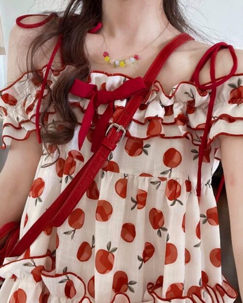 Close-up of a lolita apple dress featuring a red and white apple print, ruffles, and straps.