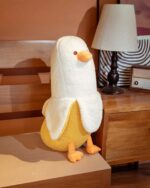 A stuffed banana duck plushie sits on a wooden surface.