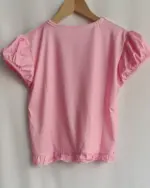 Pink kawaii pink princess t-shirt with polka dots and puffed sleeves, hanging on a hanger.