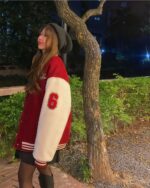Red and white korean aesthetic jacket with a number patch, worn by a woman outdoors.