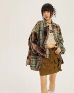 Model wearing a colorful y2k aesthetic plaid shirt over a graphic tee and a cargo mini skirt.