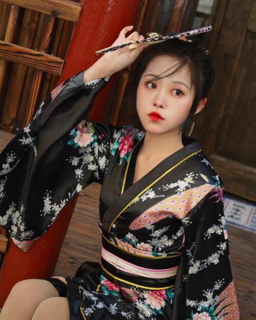 Woman wearing a short floral kimono with intricate Japanese design details outdoors.
