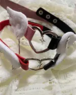 Close-up of a Winged Heart Necklace - Harajuku Aesthetic, featuring a black and red leather strap with silver heart and wing charms.