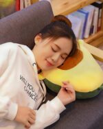 A person resting with a cute kawaii avocado plushie.