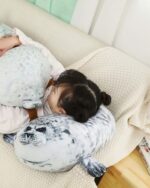 Yuki the Seal Plush resting on a sofa, a child is hugging the plush toy.
