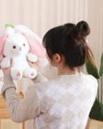 Kawaii transformable bunny plushie featuring carrot and strawberry details, held by a person.