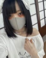 Woman wearing a kawaii loose t-shirt, grey and white, with a mask and choker.