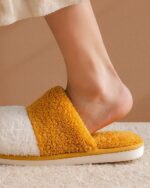 Close-up of yellow and white cat paw slippers on a foot.