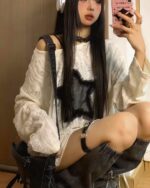 Woman wearing a grunge star top with off-shoulder detail and layered distressed denim over a plaid shirt.