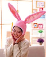Pink kawaii bunny ears hat worn by a woman indoors.