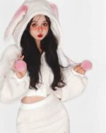 A person wearing bunny hooded plush pajamas, featuring a white fluffy design and pink accents.