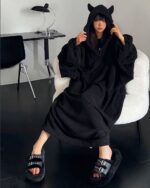 Woman wearing black little devil pajamas and fuzzy slides, kawaii decor style.