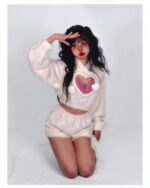 Model wearing a white kawaii fluffy pajamas set with heart detailing and pom-poms.