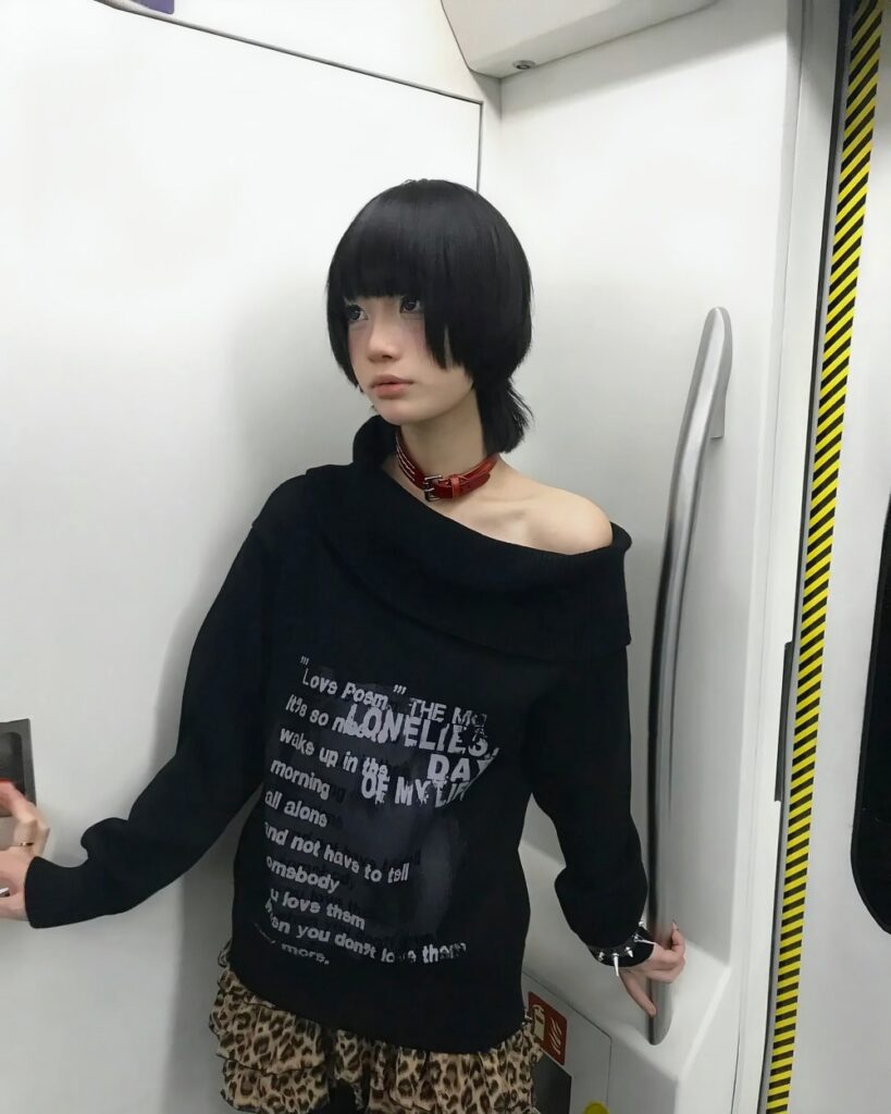 Model wearing a black grunge aesthetic sweater with an off-shoulder design.