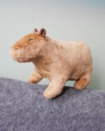 Close-up of a brown capybara plushie toy on a gray surface.