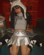 Silver pleated skirt worn by a model with a dramatic hairstyle and makeup.