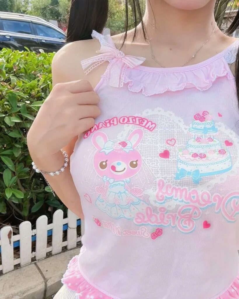 Pink mezzo piano tank top with cute character graphics and bows. Cutecore aesthetic style.